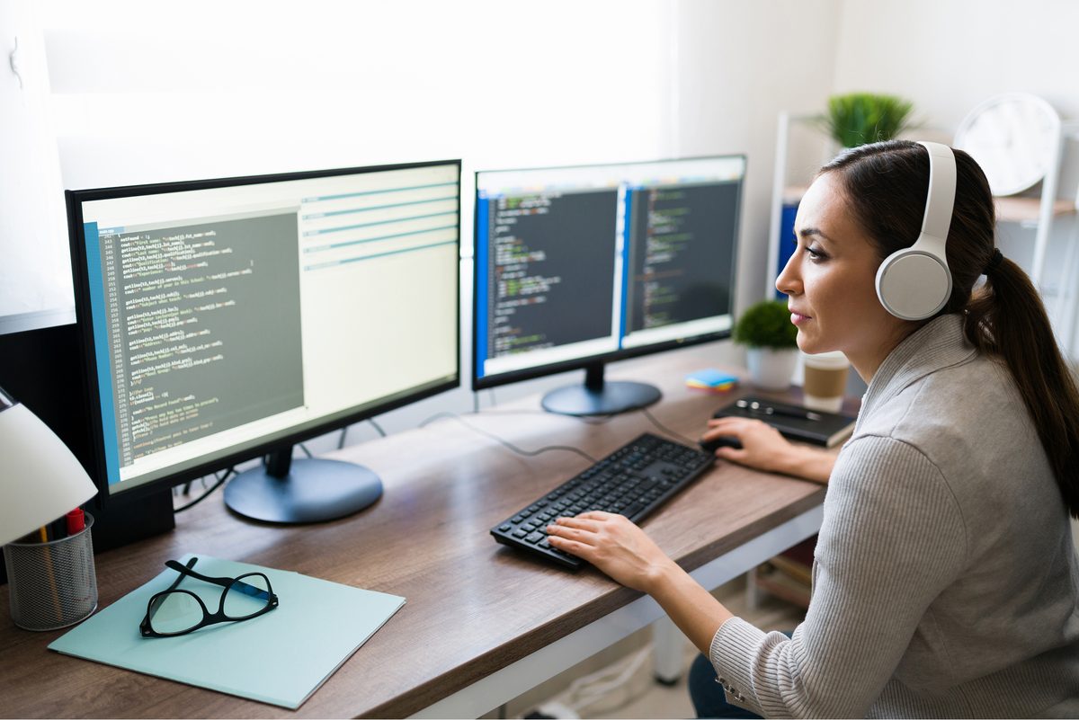 QA engineer reviewing code on a multi-monitor workstation